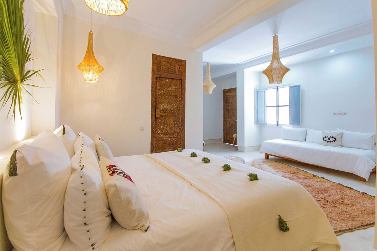A spacious bedroom with a large bed, a sofa, and a decorative door.