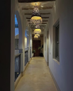 A hallway with a unique hanging light fixture, a wooden door at the end, and a potted plant. - Riad 48 & Spa (Marrakech)