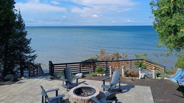 A patio with outdoor seating, a fire pit, and a view of the sea. - Sunset Paradise on Lake Michigan (Charlevoix)