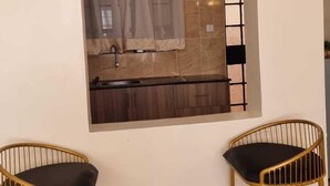 A small kitchenette with a window, two chairs, and a rug.