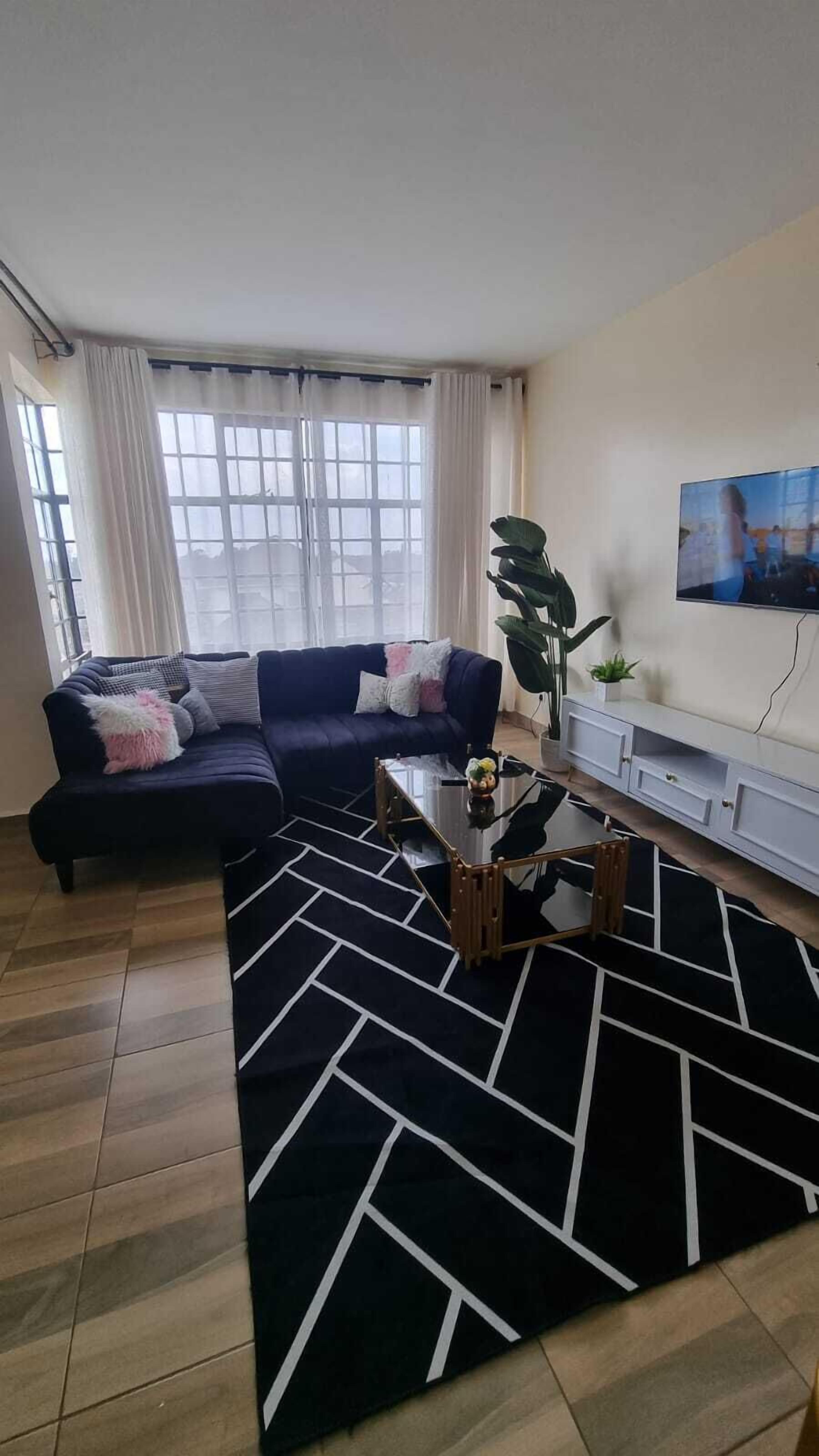 A living room with a sofa, a coffee table, and a TV on the wall.