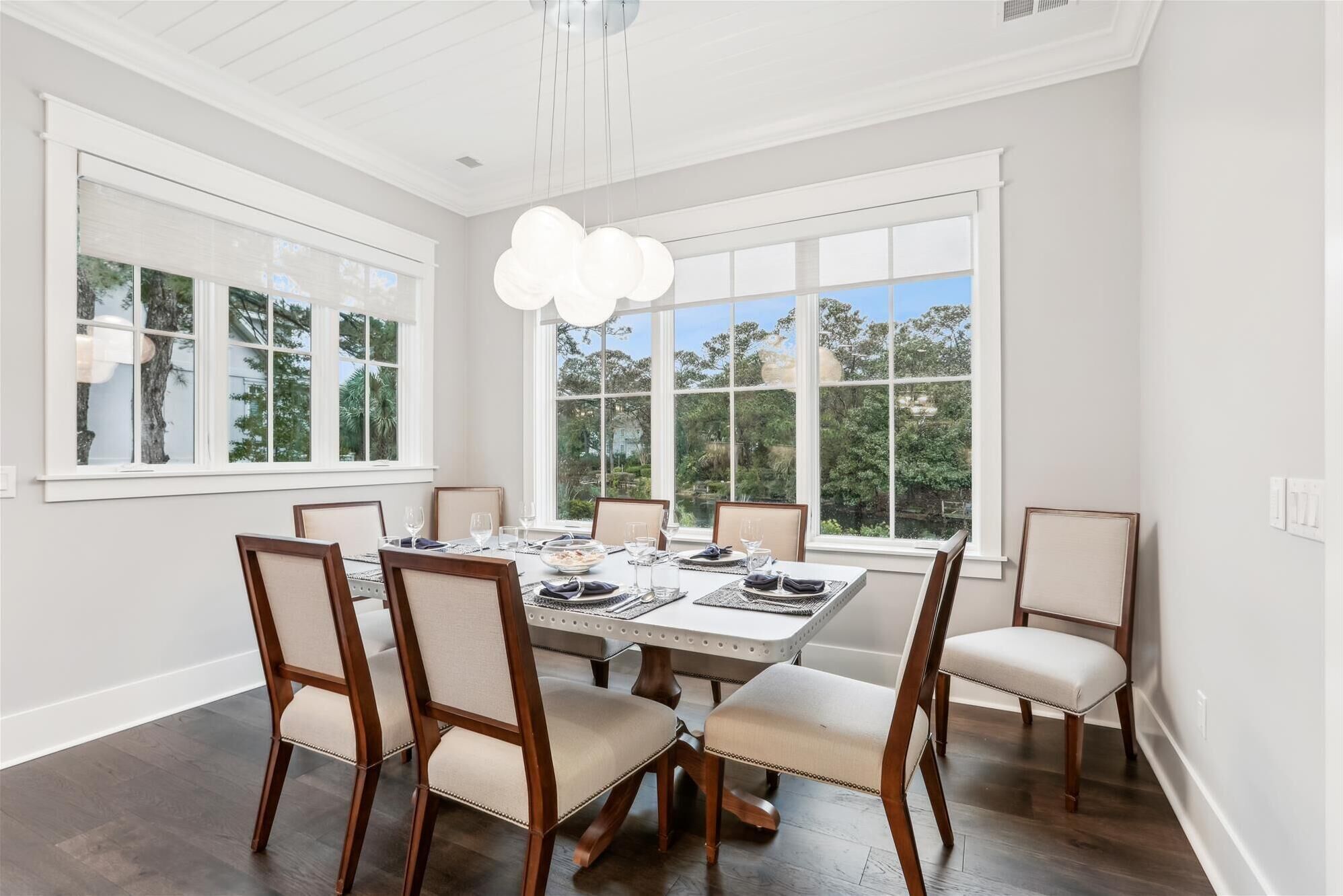 Une salle à manger avec une grande table dressée pour six personnes, entourée de six chaises dotées d’assises rembourrées.