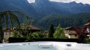 A hot tub with a mountain view, surrounded by houses and greenery. - Hotel Belfiore (Dimaro Folgarida)