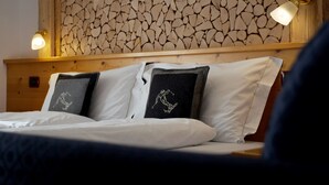 A bed with white linens and two pillows, one with a snowboard design. - Hotel Belfiore (Dimaro Folgarida)