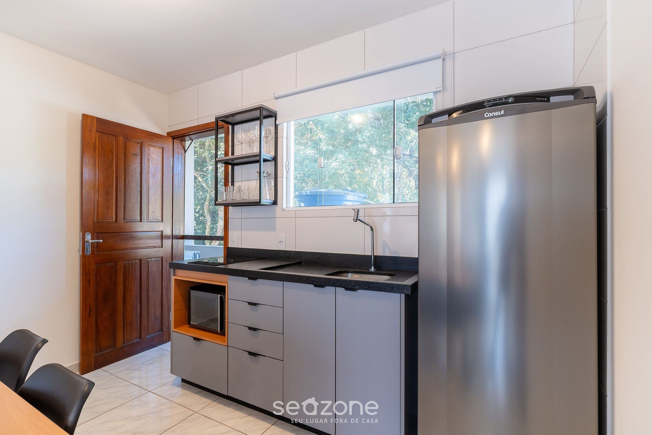 Una cucina moderna con frigorifero in acciaio inossidabile, mobili in legno e una finestra che fa entrare luce naturale.
