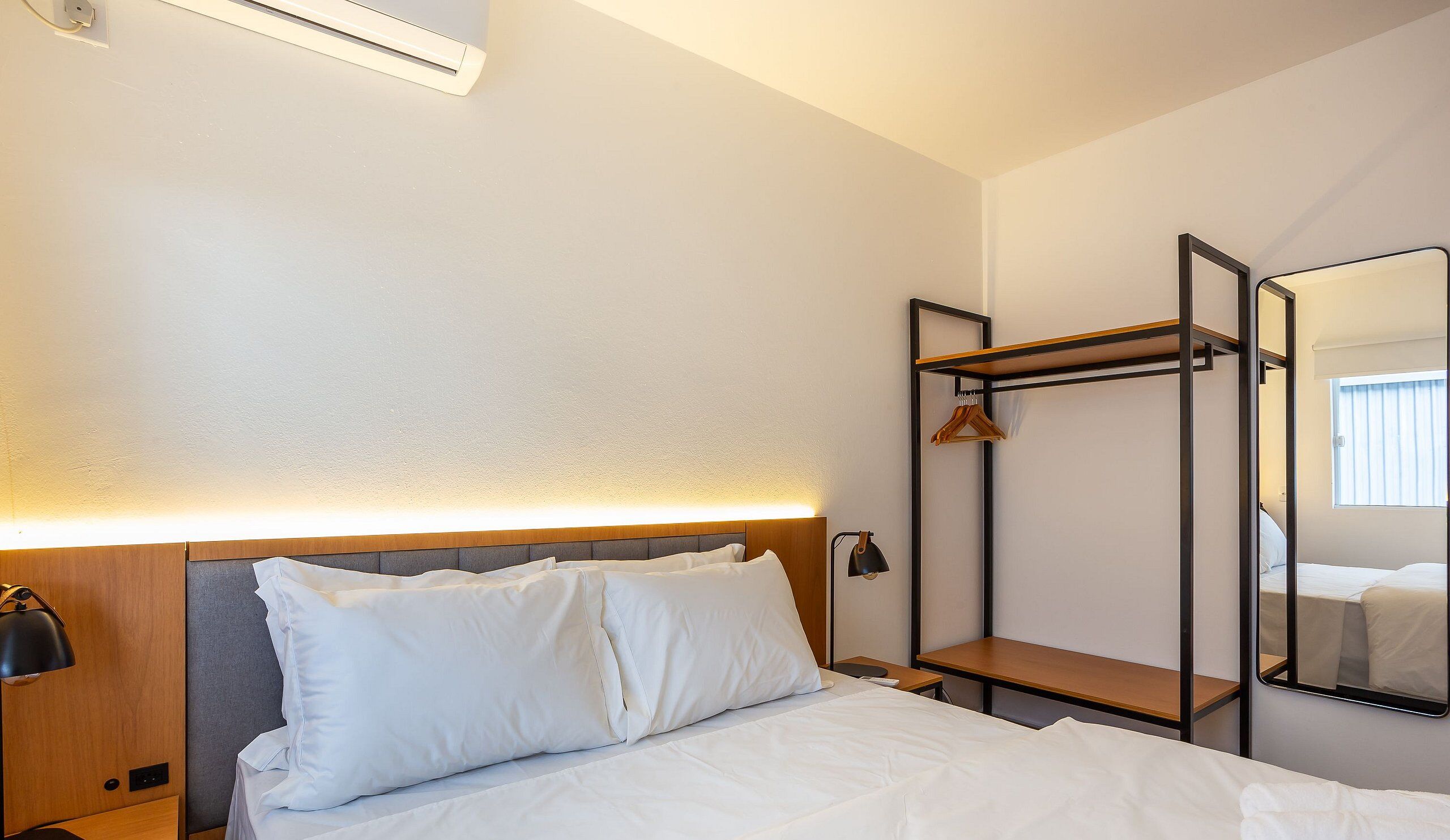 A hotel room with a bed, bedside lamp, and a mirror.