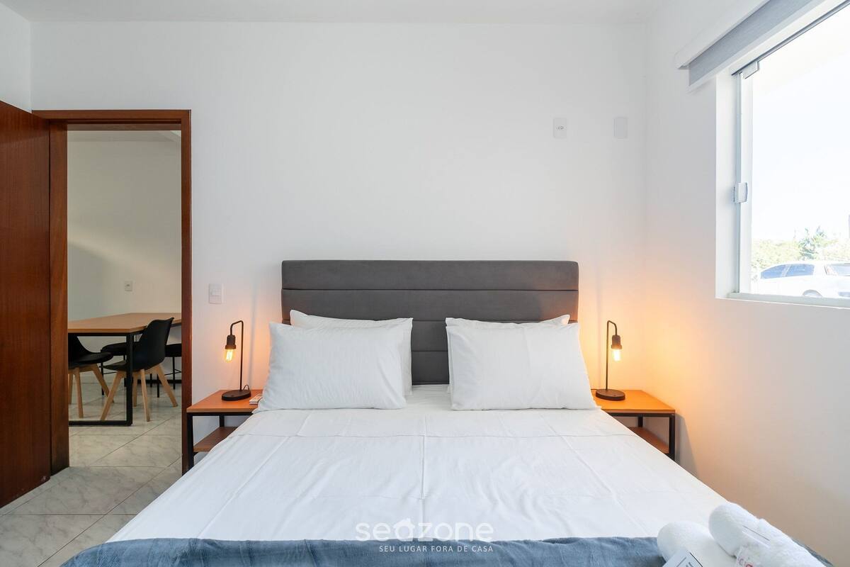 A bedroom with a bed, bedside lamps, a desk, and a chair.