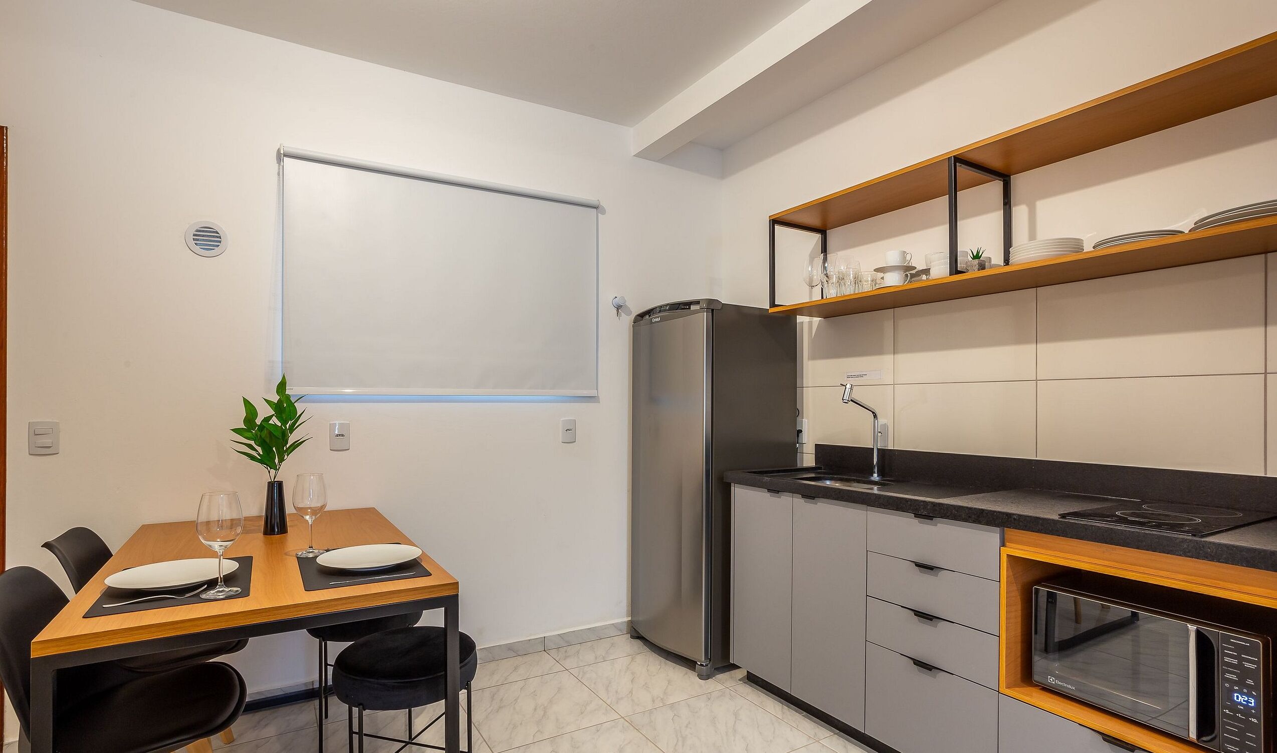 A compact kitchen with a refrigerator, microwave, and a dining area with a table and chairs.