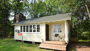 Une petite cabane à un seul étage, dotée d’une véranda, d’une cheminée et d’une boîte aux lettres.