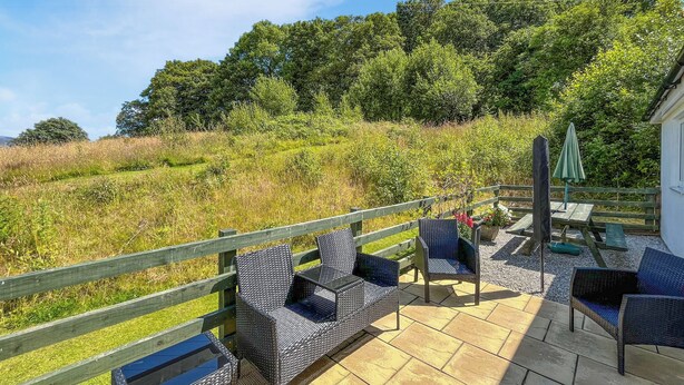 A patio with wicker furniture, a table, and an umbrella.