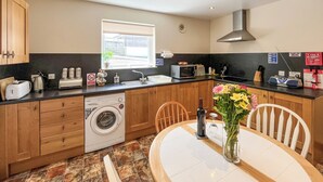 A compact kitchen with a washing machine, a sink, a microwave, and a dining area with a table and chairs.