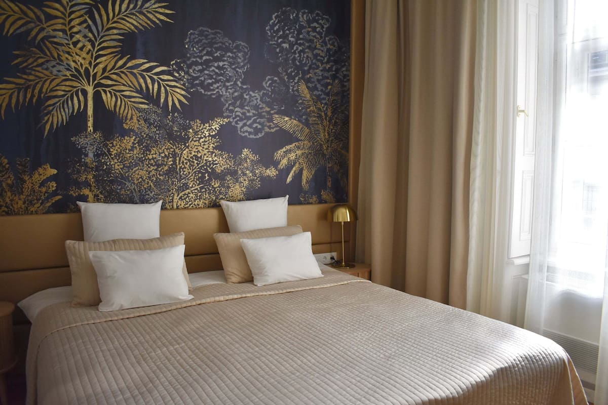 Een hotelkamer met een groot bed, een hoofdbord met een bloementapijt, en een bedlamp.