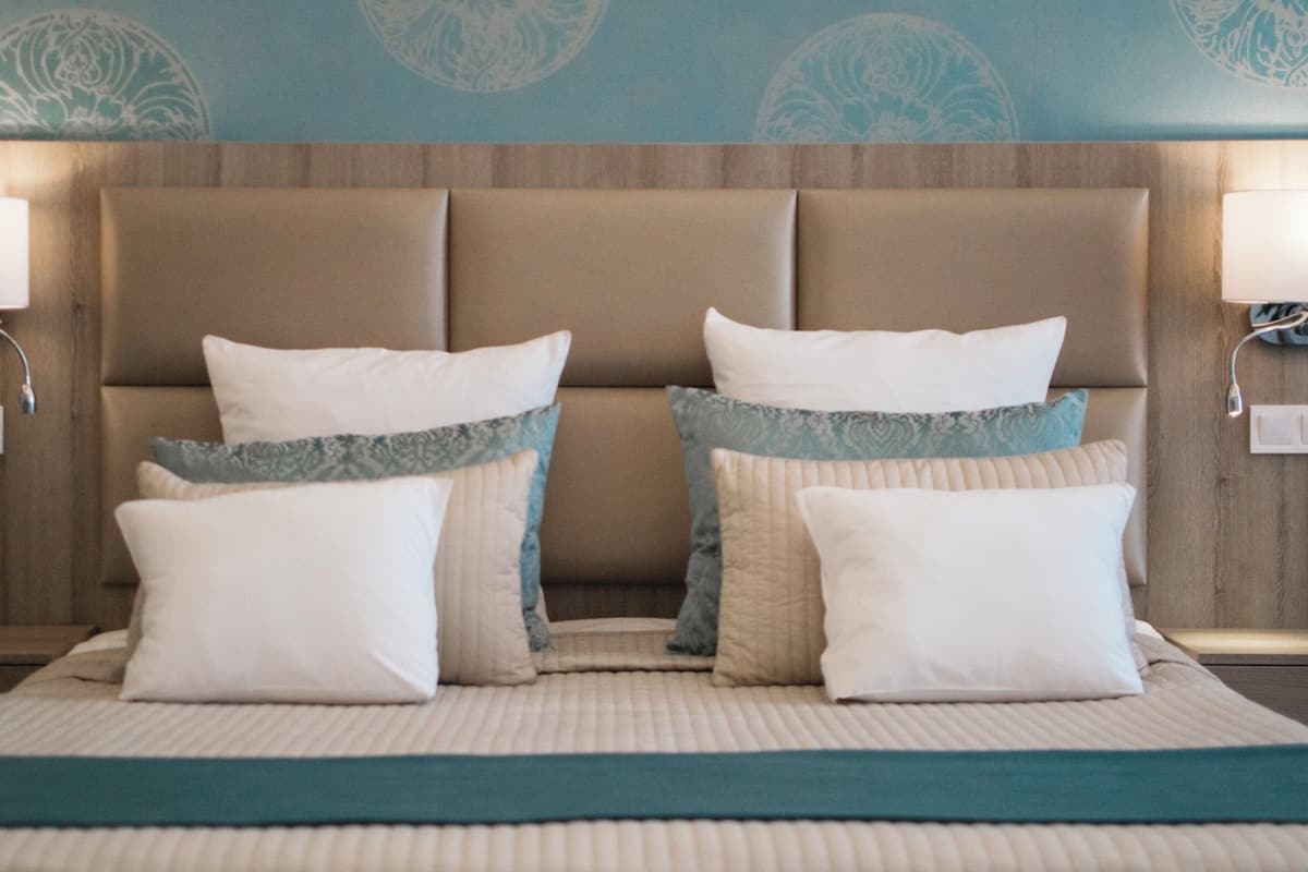 Een hotelkamer met een groot bed, twee wandlampen en een behang met een patroon.