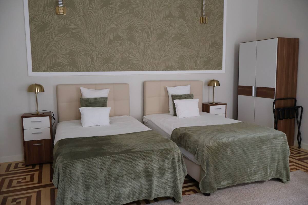 Een hotelkamer met twee bedden, een kledingkast, een nachtkastje en een groot wanddecor.