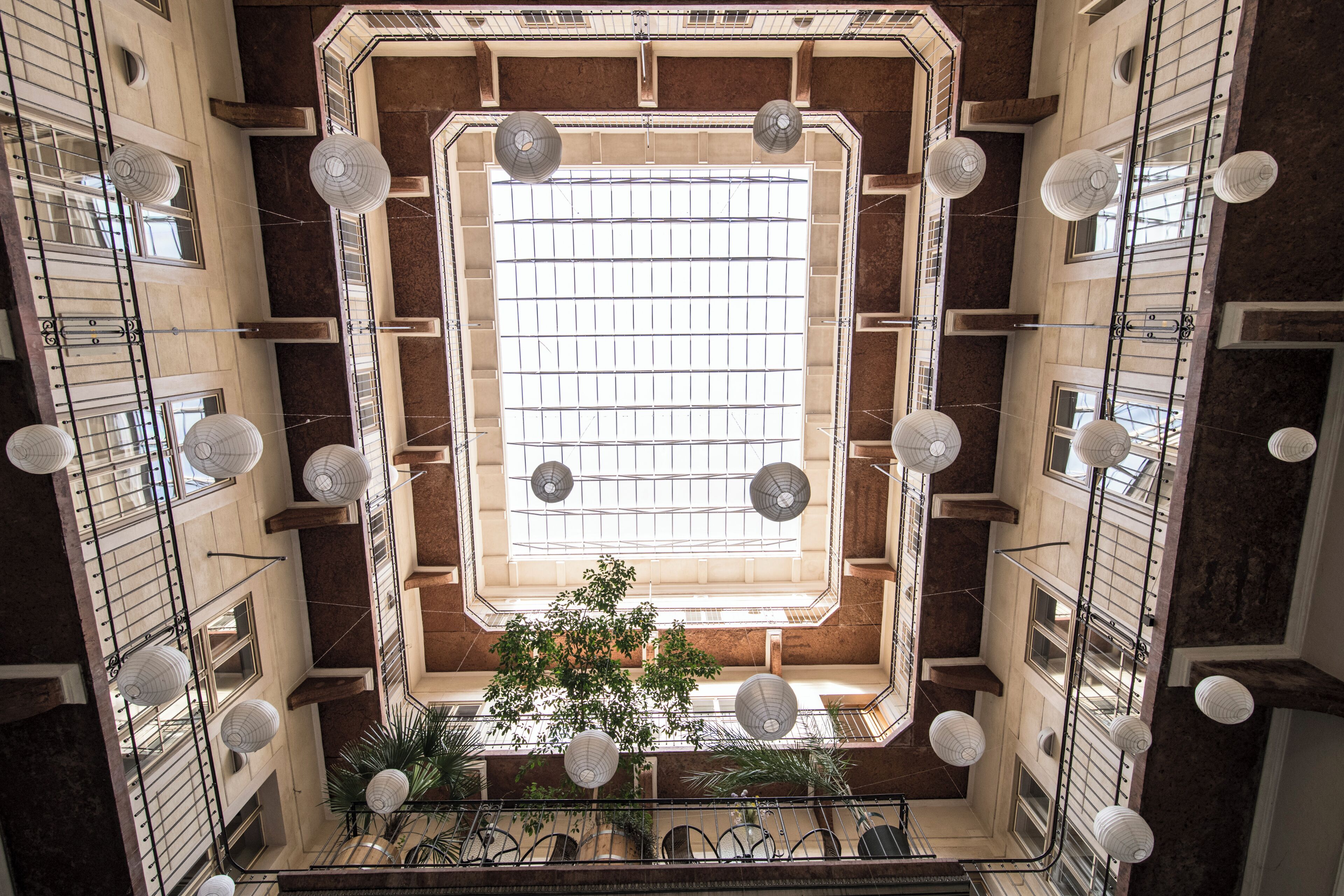 A high-ceiling atrium with a central skylight, multiple floors, and hanging lanterns.