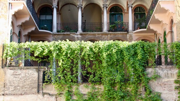 A multi-story building with a central courtyard, balconies, and a stone wall covered with ivy. - Harmonia Palace - Historic Residence (Budapest)