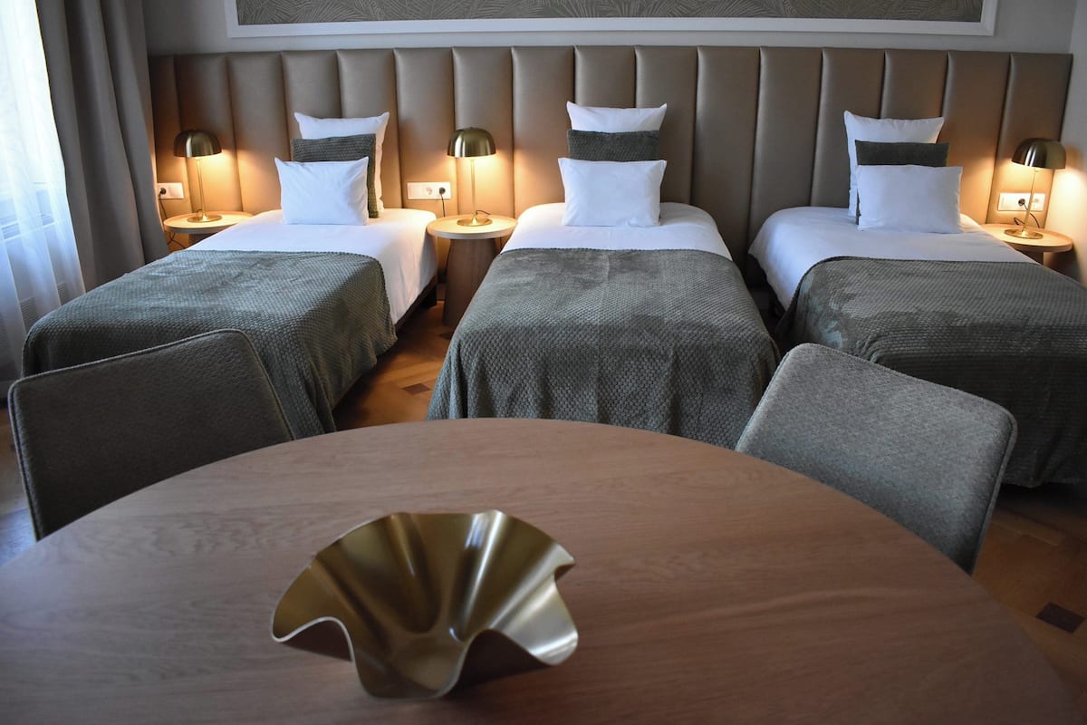 Een hotelkamer met twee enkele bedden, een ronde tafel met een decoratief middelpunt, en een modern hoofdeinde.