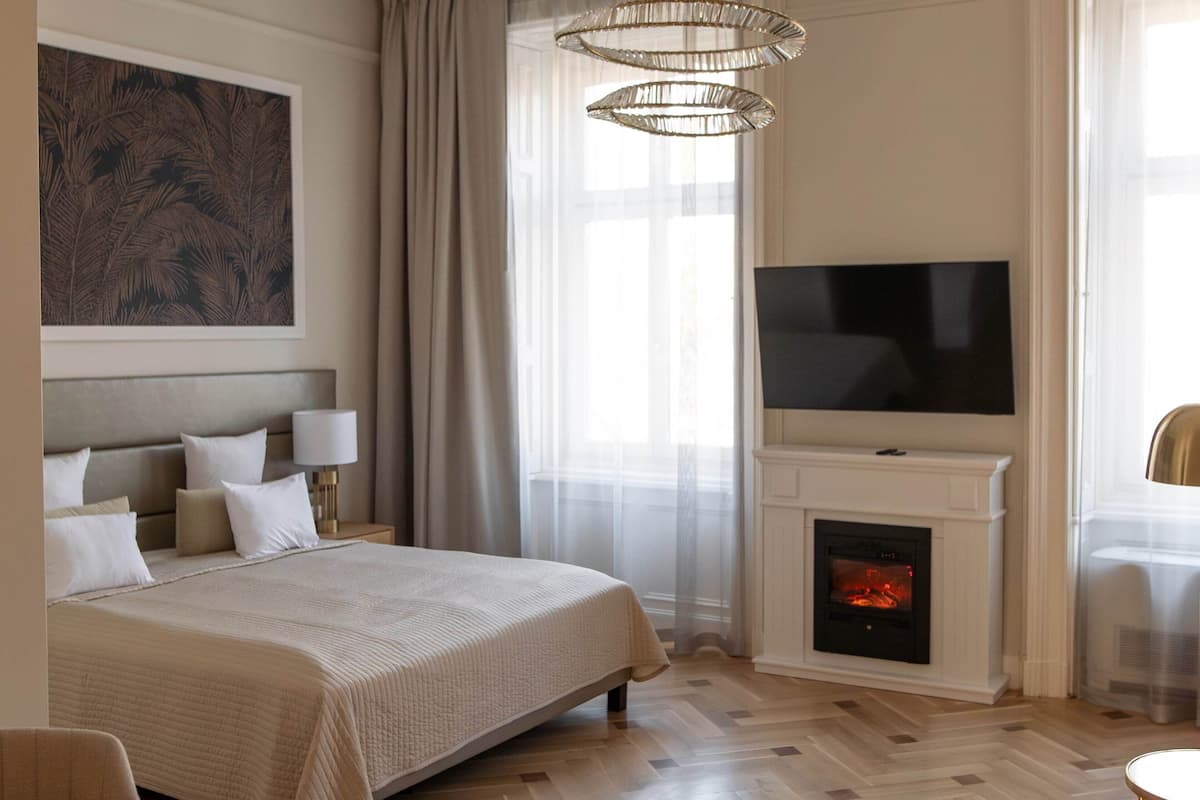 Een hotelkamer met een bed, een televisie, een open haard en een groot schilderij aan de muur.