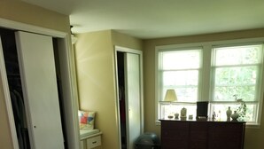 A bedroom with a bed, a dresser, a closet, and a window with blinds.