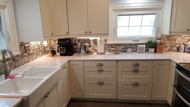 A kitchen with white cabinets, a double sink, a coffee maker, and a window above the sink.