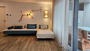 Une chambre moderne avec un canapé-lit, une petite table et une vue à travers une porte vitrée.