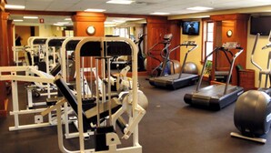 Un gimnasio con diversas máquinas de ejercicio, cintas de correr y una pantalla de televisión.