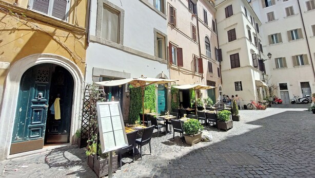 Une rue pavée avec des tables à l’extérieur et un panneau affichant le menu devant un bâtiment.