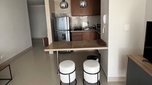 Une cuisine moderne dotée d’un îlot central, d’appareils électroménagers en acier inoxydable et de luminaires suspendus.