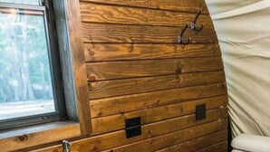 A compact bathroom with wooden walls, a sink, toilet, and a window.