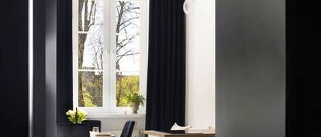 Una cocina moderna con comedor, una ventana con cortinas y vista a árboles.