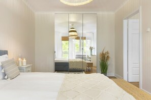 A bedroom with a bed, bedside table, and a large window. - Elite Apartments Sunset Przy PLA Y (Gdansk)