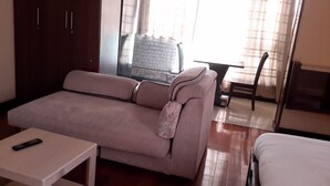 Una habitación con sofá, una mesita, una silla y una cama.