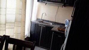 Una pequeña cocina con un lavamanos, un hervidor y un microondas.
