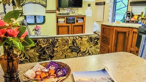 A kitchen area with a marble countertop, a vase with flowers, a basket of snacks, and a magazine titled "Explore Georgia". - Cozy Camper 2-bedroom RV in Americus GA  (Americus)
