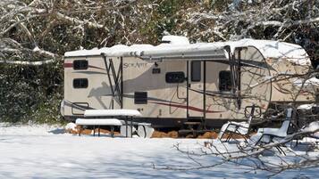 Un camper ricoperto di neve con il logo "SOLATRE", circondato da alberi e neve.