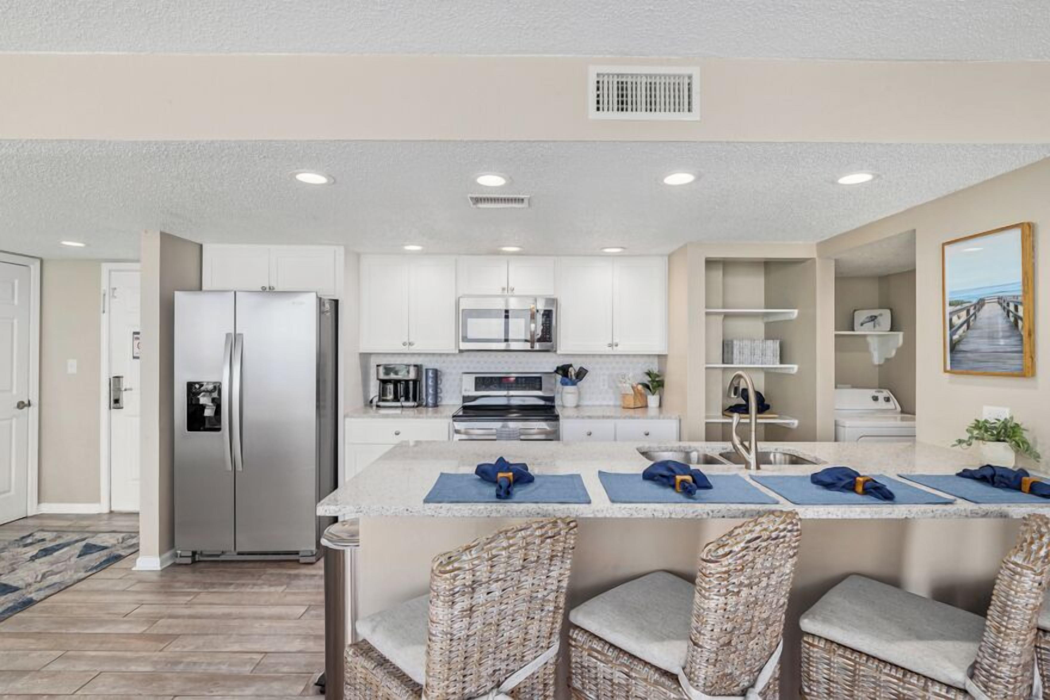 A modern kitchen with white cabinets, stainless steel appliances, and a central island with bar stools.