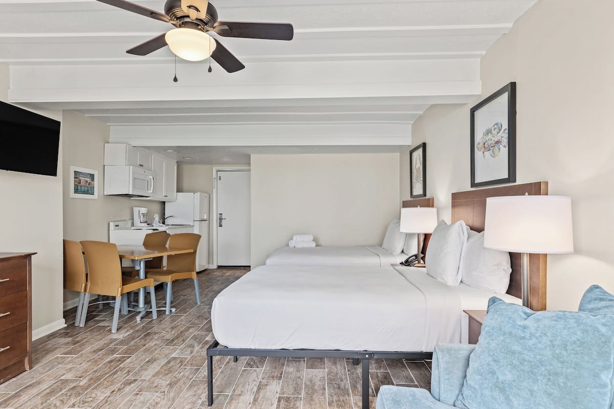 Habitación de hotel con cama, dos mesitas de noche, un escritorio con silla, microondas y ventilador de techo.