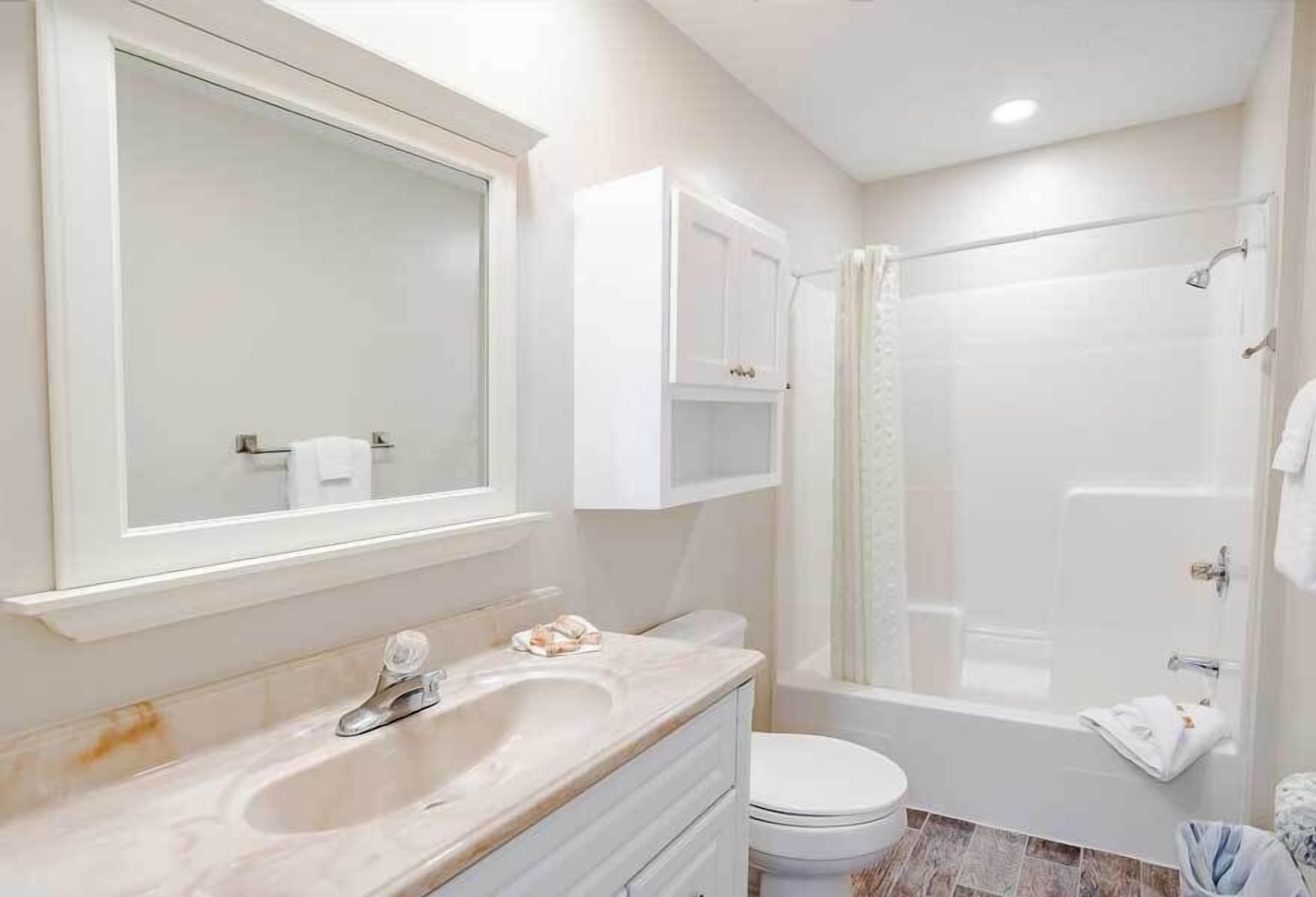 Une salle de bain équipée d’un lavabo, d’un miroir, d’un meuble de rangement, de toilettes et d’une douche.