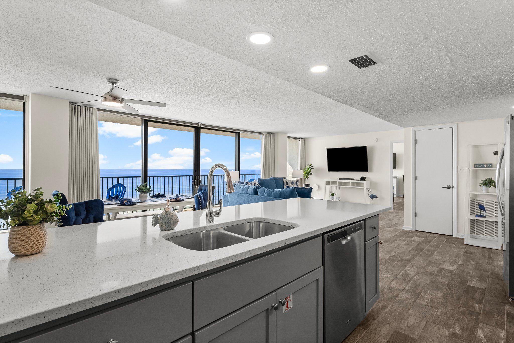 Una cocina moderna con una isla grande, un comedor con vistas y una sala de estar con sofá y televisor.