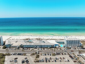 A beachfront hotel with a parking lot, beach view, and a swimming pool.