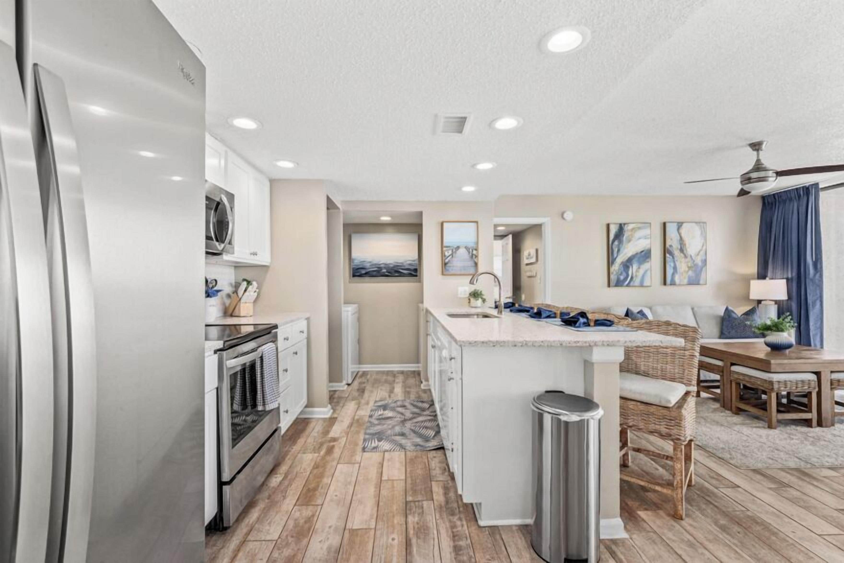 A modern kitchen with white cabinets, stainless steel appliances, and a central island.