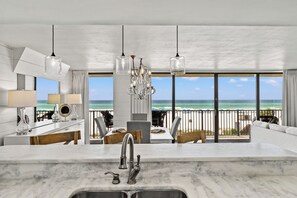 Cocina moderna con una isla grande, vistas a la playa y un comedor con asientos al aire libre.