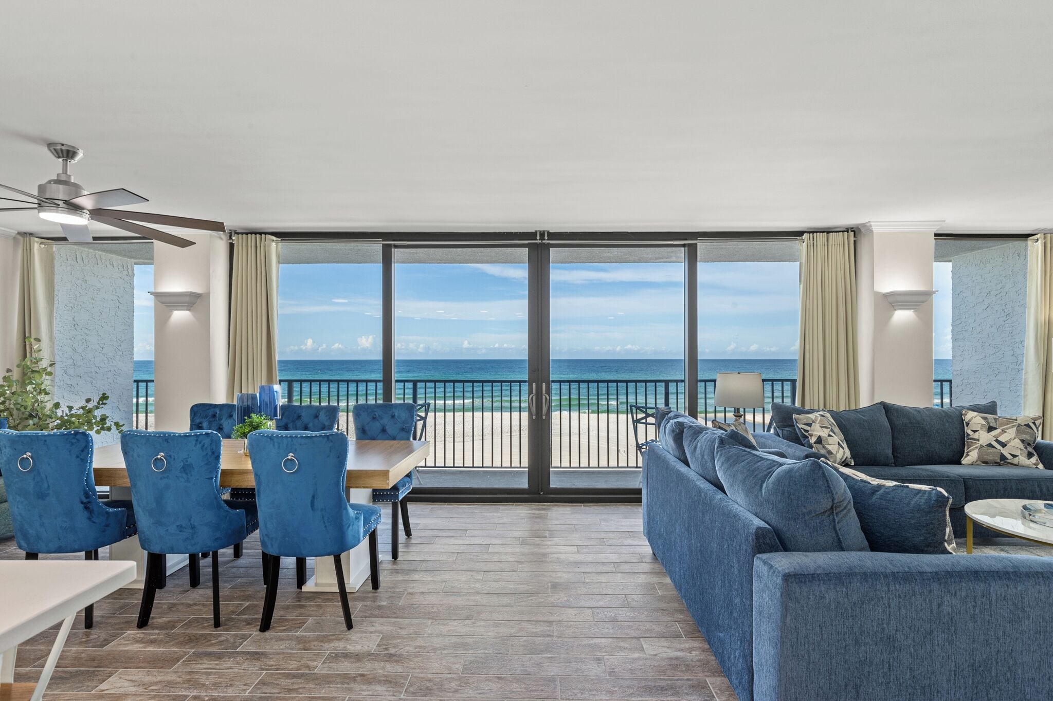 Een moderne woonkamer met een grote schuifdeur naar een balkon met uitzicht op het strand.