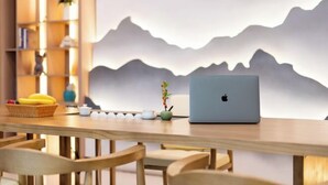 Ein Holztisch mit einem Laptop, einer Bananenkiste und einer kleinen Pflanze.