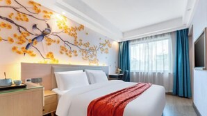 Ein Hotelzimmer mit Bett, Nachttisch, Schreibtisch mit Computer, Wand-Fernseher und einem fenster mit Vorhängen.