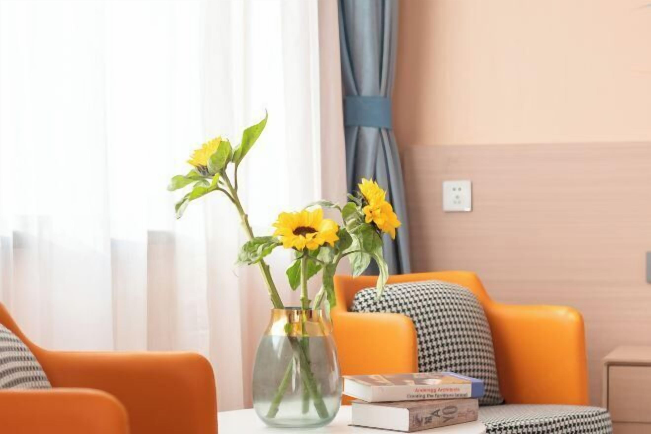 Een kamer met een bank, een tafel met een vaas zonnebloemen en een boek.
