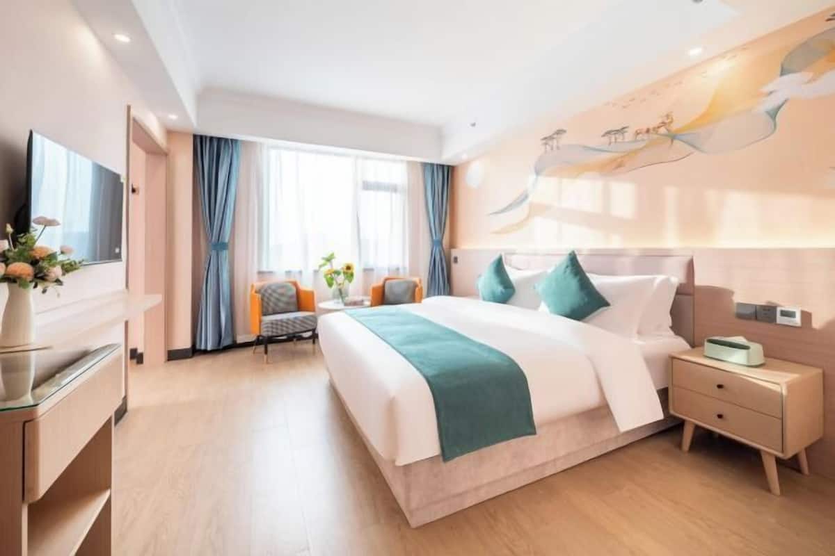 A modern hotel room with a large bed, bedside tables, a desk, and a TV.