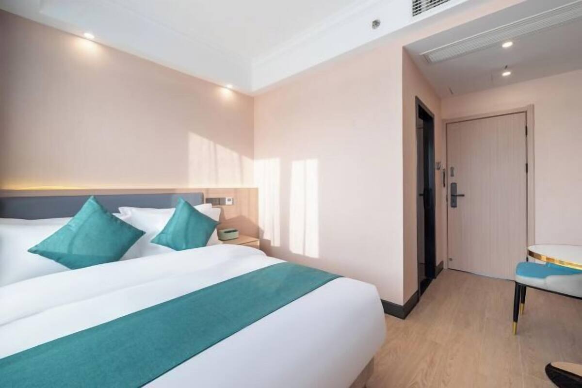 A hotel room with a large bed, a bedside table, a chair, and a door.