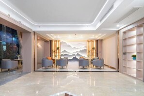 A modern hotel lobby with a marble floor, seating area, and a decorative wall with mountain imagery. - Tingquan Haina Hotel (Jinhua Vocational and Technical College) (Jinhua)