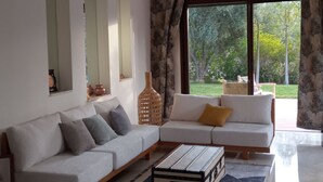 A modern living room with a sofa, a coffee table, and a large window with curtains.